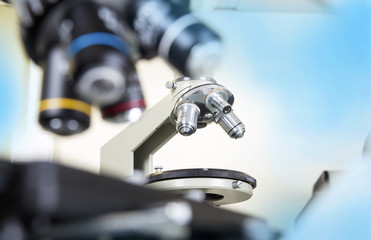 Professional microscope close-up with chemist scientific researcher hands using microscope in the laboratory interior.