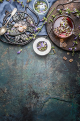 Healthy herbal tea with herbs leaves and flowers on dark rustic background. Tea with vintage tools and cup of tea, top view, place for text, border. Healthy drinks, detox or clean food concept