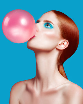 Beautiful woman close up with a bubble gum, high-quality beauty on blue background