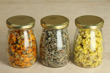 dried flowers of herbs in jars on wooden background