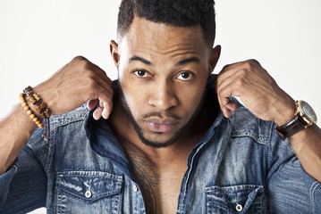African male model wearing a jean shirt looking very serious holding his collar