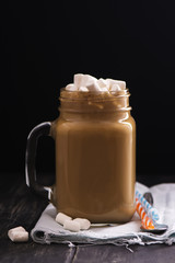 Caramel coffee in mason jar over black wooden table