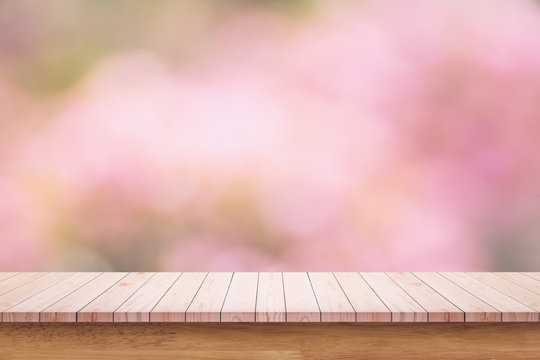 Empty wooden table with blurred pibk background.