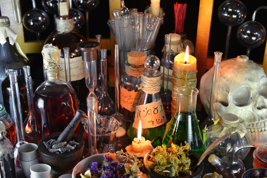 Magic bottles and burning candles on alchemy table