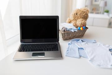 close up of baby clothes, toys and laptop at home