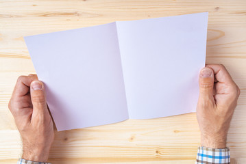 Obraz premium Man holding blank brochure as mock up copy space