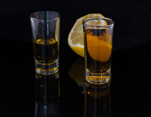 Two glasses filled with alcohol drink and a half of a lemon