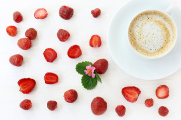 coffee strawberry background/ flat lay with red strawberries and frothy coffee on light wooden background top view 