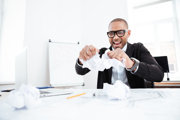 Angry businessman tearing up a document in office