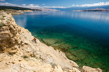 Mountain biker riding a bike on rocky trail path at sea