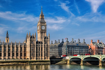 Fototapeta premium Big Ben with three double deckers buses on the bridge in London, England