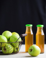 Green apples in a basket and two bottles of Apple juice.