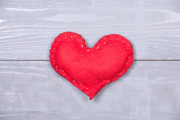 Red homemade heart natural grey wooden background.
