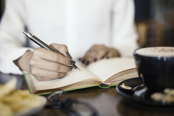 close up of a woman writing her notebook in a cafe
