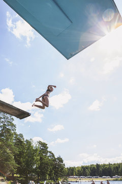 Girl jumping to water from diving board 