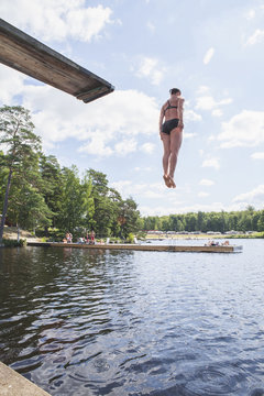 Rear View Of Mature Woman Jumping Into Lake Against Sky