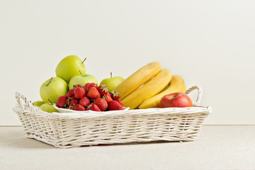 Fruits and berries on a white wicker tray.