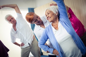 Group of seniors doing exercises with nurse
