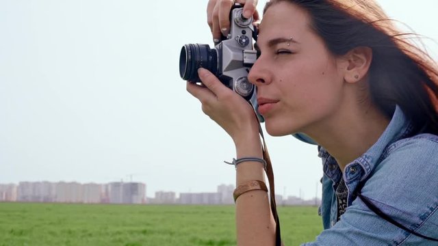 Beautiful young woman taking photos with old film camera. Slow motion