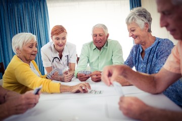 Pensioners playing cards with nurse