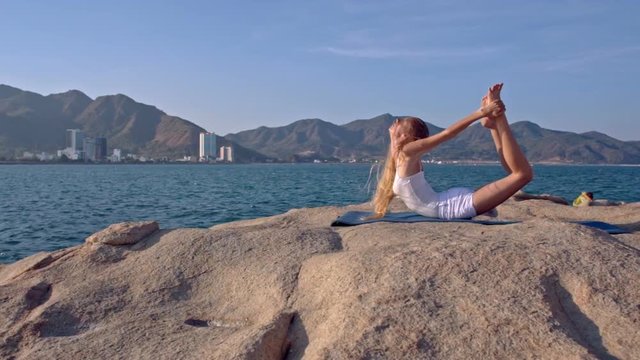 Blond Girl Does Fitness Bends Backward on Large Stone