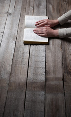 Woman hands praying with a bible in a dark over wooden table