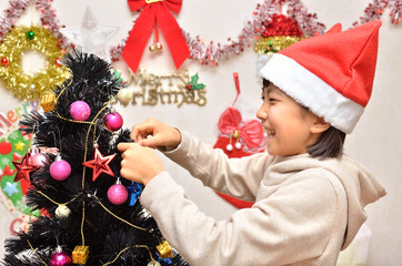 クリスマスツリーの飾りつけをする女の子
