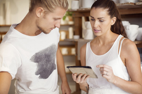 Male worker looking at female colleague using digital tablet at workshop
