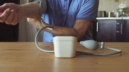 Hands of an aged man measuring the blood pressure at home
