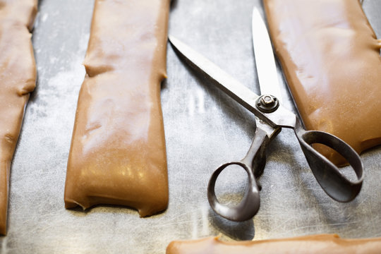 Scissors and caramel on container in candy store