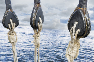 Wooden pulley on old yacht. Sea and low clouds. Replica of old vessel.