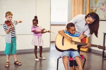 Teacher assisting a kids to play a instrument 
