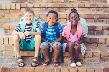 Smiling school kids sitting together on stairs