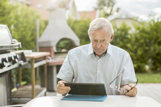 Senior man using digital tablet at table in yard