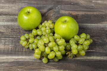 Fresh green apples and grape on wood