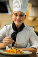 Happy head chef garnishing pasta dish with olive