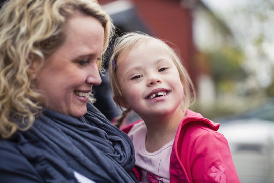 Portrait of happy girl with down syndrome carried by mother