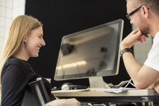 Young businessman and businesswoman looking at computer monitor in creative office