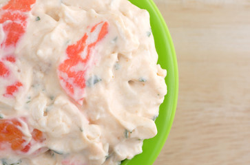 Lobster dip in green bowl on wood table top close view.
