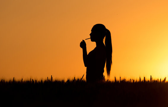Silhouette of woman lighting cigarette