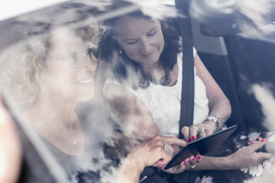 Senior women using digital tablet in car