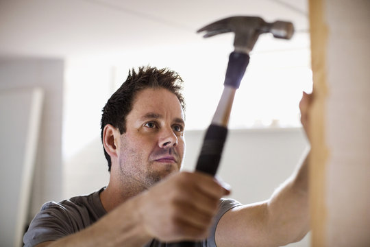 Carpenter hammering nail into wooden plank
