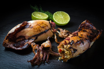 Fried squids, stuffed with rice on black dish