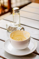 White coffee cup on wooden table with sugar shaker