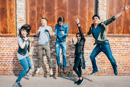 Group of young beautiful multiethnic man and woman friends having fun jumping outdoor in the city - happiness, friendship, teamwork concept