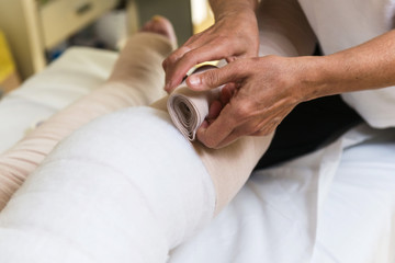 Terapista che esegue il bendaggio  elastocompressivo su arti inferiori con problemi di edema...