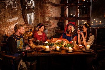 Medieval people eat and drink in ancient castle kitchen interior.