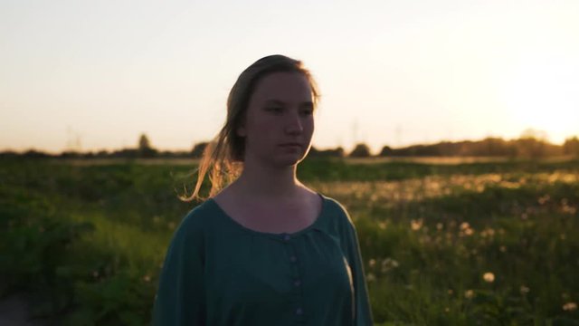 teen girl walking on old road near fields in sunset to camera shot with stabilizer