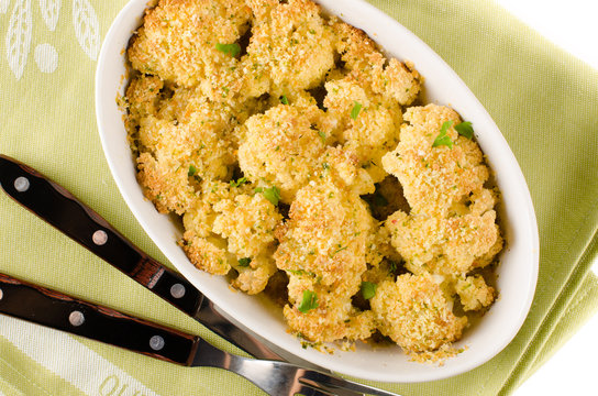 Roasted parmesan crusted cauliflower in white dish with textile
