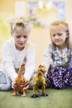 Children playing with toy dinosaurs in kindergarten